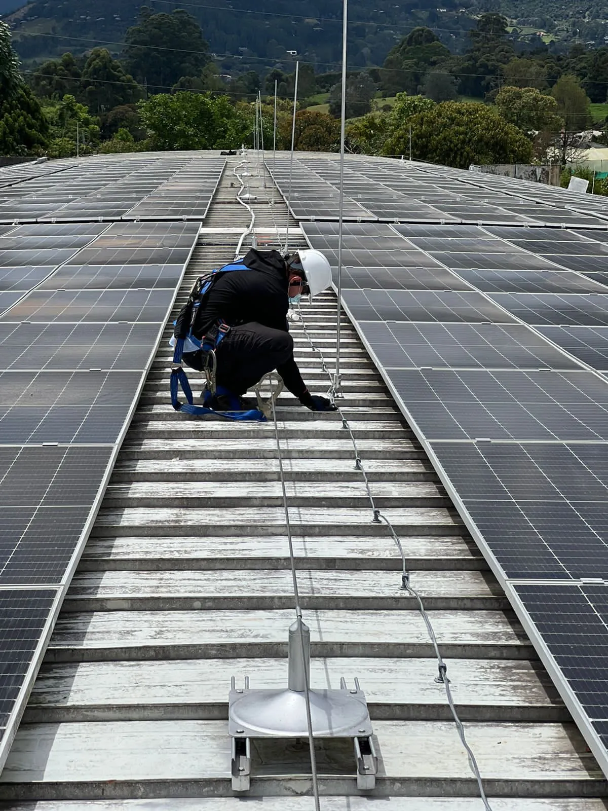 Técnico con arnés y casco instalando paneles solares en cubierta